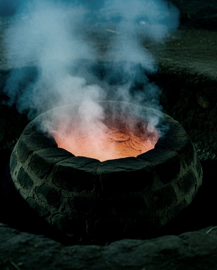 Horno de piedra subterráneo con humo y brasas — palenque tradicional